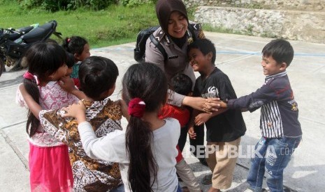 Polisi wanita bermain dengan anak-anak korban banjir bandang di tempat pengungsian sementara, Desa Pakan Rabaa Timur, Kecamatan Koto Parik Gadang di Ateh, Kabupaten Solok Selatan, Sumatra Barat, Selasa (26/11).