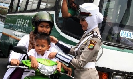 Polisi Wanita (Polwan) Bripka Novi dengan mengenakan seragam polisi berjilbab mengatur lalu lintas di lampu merah Bundaran HI, Jakarta Pusat, Senin (25/11).