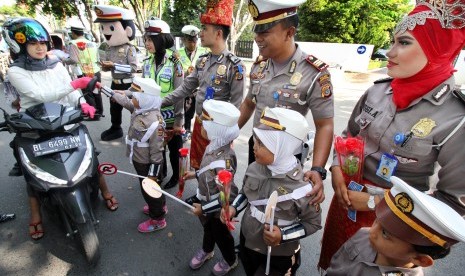 Polisi Wanita (Polwan) cilik membagikan bunga kepada pengendara motor saat Operasi Simpatik Rencong 2016 di jalan Protokol Lhokseumawe, Provinsi Aceh, Jumat (18/3).