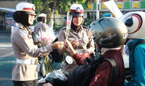 Polisi Wanita (Polwan) dari Polda DI Yogyakarta membagikan bunga dan cokelat kepada pengendara.