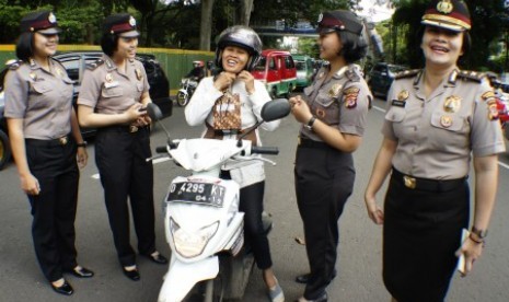 Polisi Wanita (Polwan) Polrestabes Kota Bandung membagikan cenderamata kepada pengendara motor wanita di jalan Merdeka Bandung, Jawa Barat, Selasa (22/12)