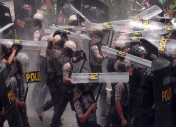 Polisi berlindung dari lemparan masa di depan PN Temanggung saat terjadi kerusuhan pada sidang vonis kasus penistaan agama, Selasa (8/2).