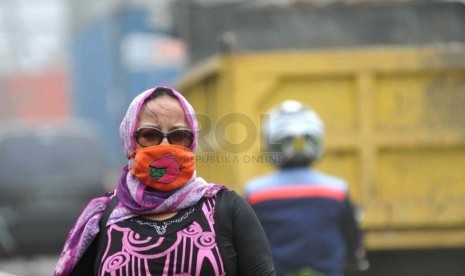 Polus Udara Jalanan. Pejalan kaki menggunakan masker untuk menyaring pekatnya debu di kawasan Koja, Jakarta Utara, Senin (17/3).