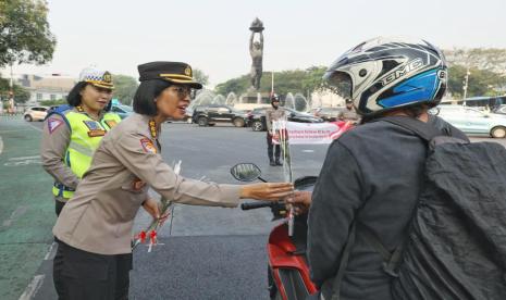 Polwan bagikan bunga ke pengguna jalan.