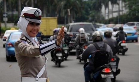  Polwan berjilbab mengatur mengatur lalu lintas di lampu merah Bundaran HI, Jakarta Pusat . 