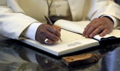 Pope Francis writes a note in the guest book during his visit to the residence of Israel's President Shimon Peres in Jerusalem May 26, 2014.