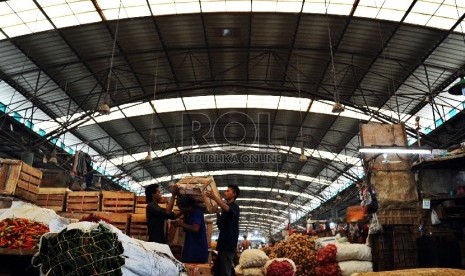 Porter melintas saat memanggul sayur mayur di pasar Induk Kramat Jati, Jakarta, Kamis (23/7).