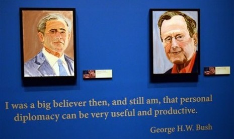 Portraits of former Presidents Goerge W. Bush (left) and his father George H.W. Bush are on display at the George W. Bush Presidential Library and Museum in Dallas, Friday, April 4, 2014.