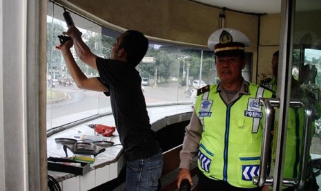 Pos Polisi Rusak: Petugas memeriksa bagian pintu yang hancur di Pos Polisi Bundaran Senayan, Jakarta Pusat, Ahad (9/2). Pospol TL CSW di Jalan Trunojoyo, Jakarta Selatan juga dirusak orang tak dikenal malam tadi.