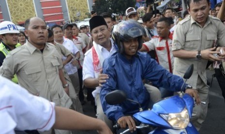 Prabowo Subianto naik sepeda motor saat mengunjungi pasar Tanah Abang, Jakarta, Jumat (20/6). 