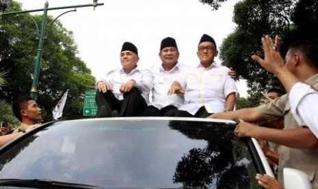 Prabowo Subianto (tengah) dan Hatta Rajasa (kiri) didampingi Aburizal Bakrie (kanan) menyapa pendukungnya saat meninggalkan gedung KPU usai menyerahkan berkas kelengkapan pendaftaran untuk mengikuti pilpres di halaman Gedung KPU, Jakpus, Selasa (20/5). 