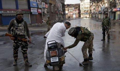 OKI Tolak Tindakan Ilegal India di Kashmir. Prajurit Paramiliter India memeriksa tas seorang pria yang mengendarai skuter saat jam malam di Srinagar, Kashmir yang dikuasai India, Kamis (8/8).