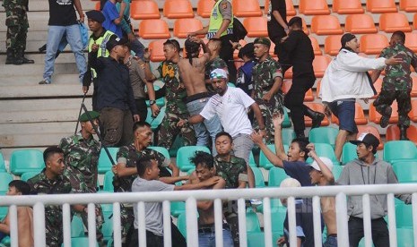 Prajurit TNI AD membubarkan aksi suporter tim sepak bola Jabar yang terlibat bentrok dengan suporter tim sepak bola DKI Jakarta pada babak penyisihan grup A PON XIX di Stadion Pakansari, Cibinong, Bogor, Jawa Barat, Minggu (18/9).