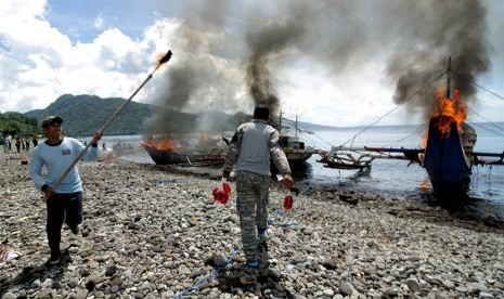 Prajurit TNI AL memusnahkan kapal penangkap ikan ilegal berbendara negara asing dengan cara dibakar di Pangkalan Angkatan Laut (Lanal) Kota Tahuna, Kepulauan Sangihe, Sulawesi Utara, Kamis (31/12). (Antara/Stenly Pontolawokang)