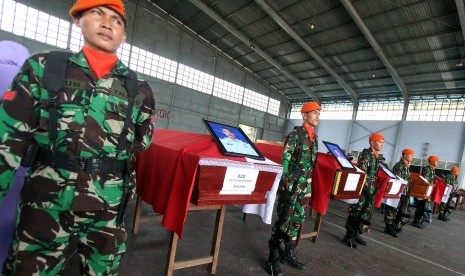 Prajurit TNI AU berdiri disamping peti jenazah prajurit TNI yang menjadi korban jatuhnya pesawat Hercules C-130 saat proses pengembalian jenazah korban di Lanud Soewondo Medan, Sumatera Utara, Rabu (1/7). (Antara//Septianda Perdana)