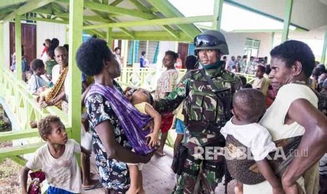 Prajurit TNI berbincang dengan warga saat menunggu antrean berobat di puskesmas Ayam di kampung Bayiwpinam, Distrik Akat, Kabupaten Asmat, Papua, Jumat (26/1).