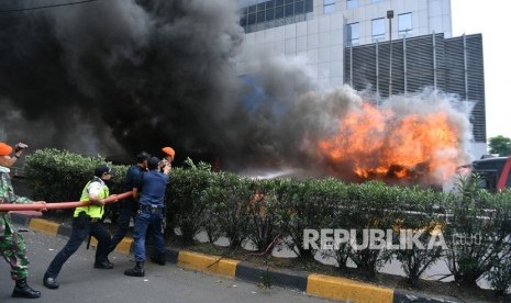 Prajurit TNI bersama warga mencoba memadamkan api yang membakar bus milik Brimob di kawasan Slipi, Jakarta Barat, Rabu (22/5/2019).