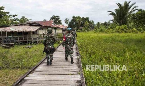 Prajurit TNI dan petugas kesehatan yang tergabung dalam Satgas penanggulangan KLB Campak dan Gizi buruk di Asmat berjalan menuju Puskesmas Ayam di kampung Bayiwpinam, Distrik Akat, Kabupaten Asmat, Papua, Jumat (26/1). 