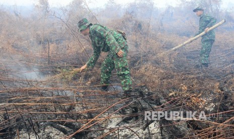 Prajurit TNI dari Kodim 0105 Aceh Barat memadamkan api dengan cara manual di kawasan lahan gambut yang terbakar di Desa Suak Raya, Johan Pahlawan, Aceh Barat, Aceh, Selasa (25/7). 