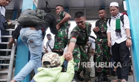 Prajurit TNI membantu peserta kegiatan Reuni 212 yang hendak menyeberang ke Stasiun Juanda, Jakarta Pusat, dari Masjid Istiqlal, Jakarta Pusat, Ahad (2/12). Peserta kegiatan Reuni 212 harus melompat ke halte bus Transjakarta untuk bisa cepat sampai ke Stasiun Juanda.