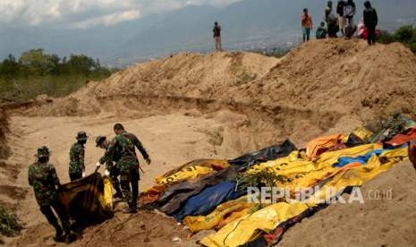 Prajurit TNI mengangkat jenazah korban gempa Palu di TPU Poboya Indah, Palu, Sulawesi Tengah, Selasa (2/10). 