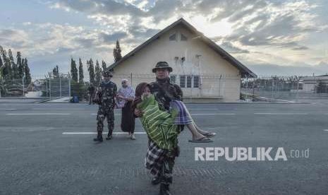 Prajurit TNI mengendong Korban gempa selamat di Bandara Mutiara Sis Aljufri untuk di evakuasi di Palu, Sulawesi Tengah, Sabtu (29/9). 