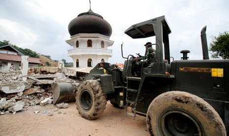 Prajurit TNI mengoperasikan alat berat untuk membersihkan puing Masjid Jamik Quba yang roboh akibat gempa bumi 6,5 SR di Pidie Jaya, Aceh, Sabtu (10/12).