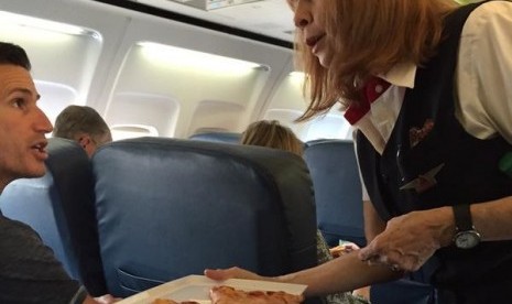 Pramugari Delta Airlines memberikan pizza kepada penumpang