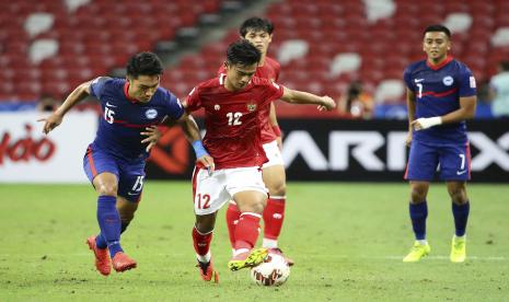 Pratama Arhan Alif Rifai dari Indonesia, kanan, mengontrol bola melawan Song Uiyoung dari Singapura pada pertandingan leg kedua semifinal AFF Suzuki Cup 2020 antara Indonesia dan Singapura di Singapura, Sabtu 25 Desember 2021.