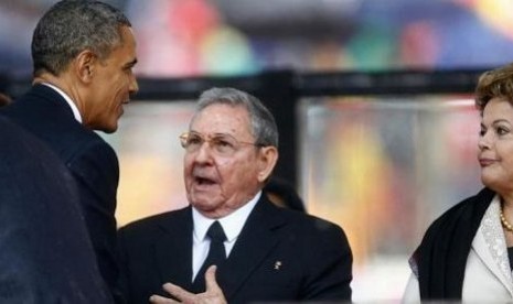 Presiden AS Barack Obama (kiri) menjabat tangan Pemimpin Kuba, Raul Castro, sesaat sebelum memberikan pidato dalam acara peringatan dan pemakaman Nelson Mandela di Soweto, Afrika Selatan, Selasa (10/12/2013)