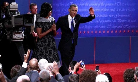  Presiden AS Barack Obama melambaikan tangan didampingi Michelle Obama saat meninggalkan panggung debat final  presiden AS di Boca Raton, Florida, Selasa (23/10). (Jason Reed/Reuters)