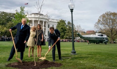 Presiden AS Donald Trump dan Presiden Prancis Emmanuel Macron menanam pohon ek simbol persahabatan di sisi selatan Gedung Putih pada April 2018. Keduanya ditemani ibu negara masing-masing.