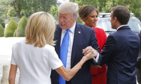 Presiden AS Donald Trump (kedua kiri) menyapa hangat Ibu Negara Prancis Brigitte (kiri). Tampak Presiden Prancis Emmanuel Macron menyambut Melania Trump di Paris, 13 Juli 2017.