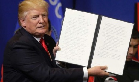 Presiden AS Donald Trump memegang kertas inpres sebelum menandatanganinya.  