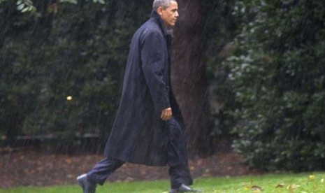   Presiden Barack Obama di tengah hujan deras berjalan menuju Gedung Putih di Washington, Senin (29/10) waktu setempat.  (Jacquelyn Martin/AP)