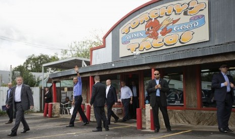 Presiden Barack Obama melambaikan tangan usai keluar dari kedai taco sambil menenteng pesanan makanannya, Jumat (11/3), di Texas.