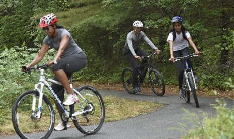 Presiden Barack Obama, putrinya Malia dan Ibu Negara Michelle Obama (kiri) saat bersepeda di West Tisbury, Massachussets di Martha's Vineyard.