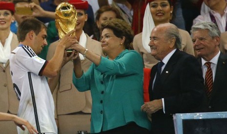 Presiden Brasil, Dilma Rousseff (dua kiri), menyerahkan trofi Piala Dunia kepada kapten Timnas Jerman, Philipp Lahm, usai memenangkan partai final mengalahkan Argentina 1-0 di Stadion Maracana, Rio de Janeiro, Ahad (13/7). 