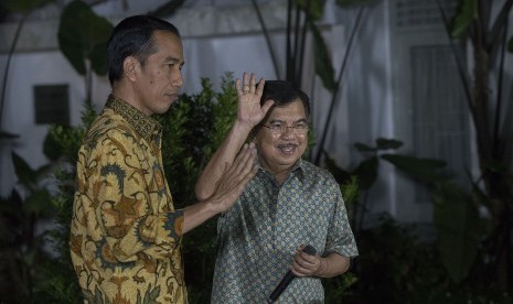 Presiden dan Wakil Presiden terpilih, Joko Widodo (kiri) dan Jusuf Kalla (kanan) melambaikan tangan usai memberikan konferensi pers di halaman Rumah Dinas Gubernur DKI Jakarta di Taman Suropati Nomor 7, Jakarta, Kamis (21/8) malam. 