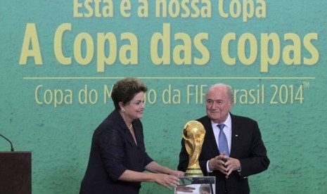 Presiden FIFA, Sepp Blatter (kanan), dan Presiden Brasil, Dilma Rousseff, berpose bersama trofi Piala Dunia di Planalto Palace, Brasilia, Senin (2/6). 