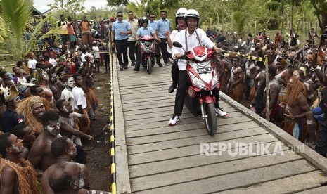 Presiden Joko Widodo berboncengan dengan Ibu Negara Iriana Joko Widodo menggunakan motor listrik menyapa warga Asmat saat kunjungan kerja di Kampung Kaye, Distrik Agats, Kabupaten Asmat, Papua, Kamis (12/4).