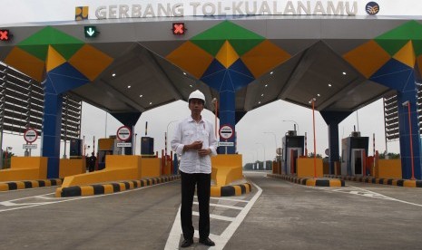 Presiden Joko Widodo berdiri di depan pintu masuk tol ketika meninjau Jalan Tol Trans Sumatera ruas gerbang tol Kualanamu saat diresmikan di Deli Serdang, Sumatera Utara, Jumat (13/10). 