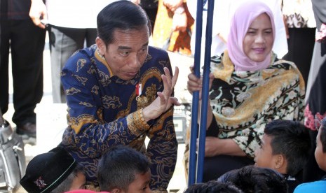 Presiden Joko Widodo dan Ibu Negara Iriana menghibur dan membagi buku bacaan kepada anak korban gempa di tenda pengungsian Ringblang Meurdu, Pidie Jaya, Provinsi Aceh, Kamis (15/12). 