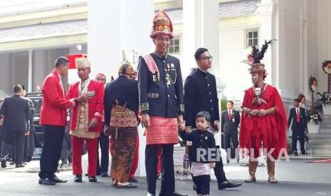 Presiden Joko Widodo (Jokowi) mengenakan pakaian adat asal Aceh untuk memperingati detik-detik proklamasi Kemerdekaan RI di Istana Merdeka, Jakarta, Jumat (17/8). Ia tampak bersama putranya Gibran Rakabuming dan cucunya Jan Ethes Srinarendra. 