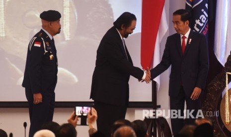 Presiden Joko Widodo (kanan) berjabat tangan dengan Ketua Umum Partai Nasdem Surya Paloh (tengah) disaksikan Gubernur Akademi Bela Negara IGK Manila saat Peresmian Akademi Bela Negara di Jakarta, Minggu (16/7). 