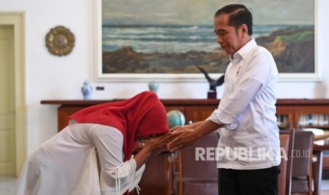 Presiden Joko Widodo (kanan) bersalaman dengan terpidana kasus pelanggaran Undang-Undang Informasi dan Transaksi Elektronik (ITE) Baiq Nuril Maknun di Istana Bogor, Jawa Barat, Jumat (2/8/2019). 