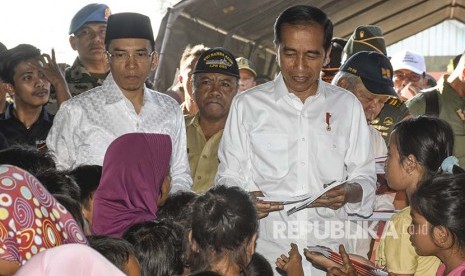 Presiden Joko Widodo (kanan) didampingi Gubernur NTB TGB Zainul Majdi (kedua kiri) membagikan buku kepada anak-anak korban gempa di Desa Madayin, Kecamatan Sambelia, Selong, Lombok Timur, NTB, Senin (30/7). 