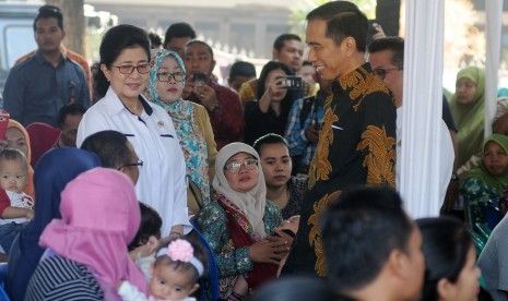 Presiden Joko Widodo (kanan) didampingi Menteri Kesehatan Nila F Moeloek (kiri) berbincang dengan orangtua korban vaksin palsu saat meninjau pelaksanaan vaksinasi ulang di Puskesmas Kecamatan Ciracas, Jakarta Timur, Senin (18/7).