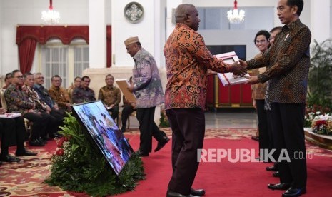 Presiden Joko Widodo (kanan) didampingi Wakil Presiden Jusuf Kalla (kedua kanan) dan Menkeu Sri Mulyani menyerahkan Daftar Isian Pelaksanaan Anggaran (DIPA) dan Daftar Alokasi Transfer Daerah dan serta Dana Desa kepada Gubernur Papua Barat Dominggus Mandacan di Istana Negara, Jakarta, Selasa (11/12/2018).