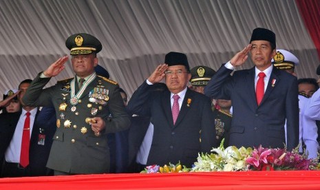 Presiden Joko Widodo (kanan) didampingi Wapres Jusuf Kalla (tengah) dan Panglima TNI Jenderal TNI Gatot Nurmantyo (kiri) memberi hormat pada Upacara Parade dan Defile HUT ke-72 TNI Tahun 2017 di Dermaga Indah Kiat, Cilegon, Banten Kamis (5/10). 